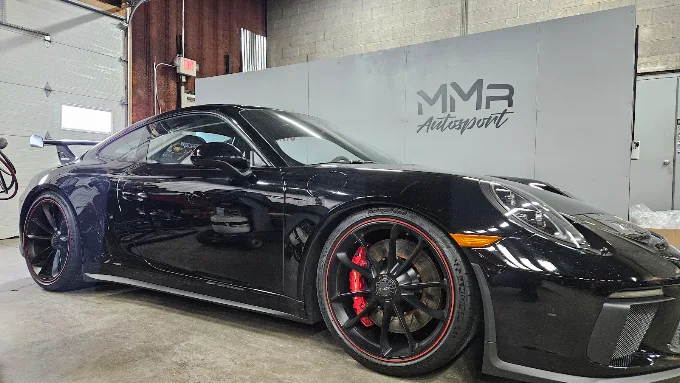 Black Porsche 911 GT3 with red brake calipers inside MMr Autosport