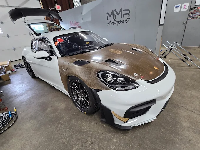 White Porsche Cayman race car with exposed carbon-fiber front bodywork