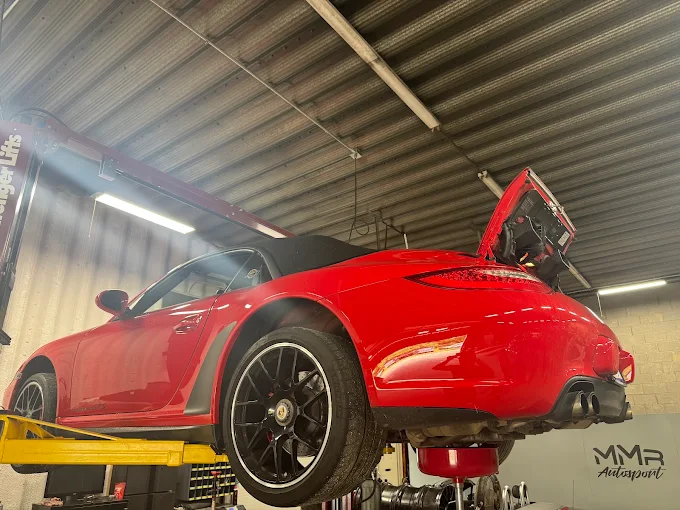 Red Porsche 911 raised on a lift inside MMr Autosport