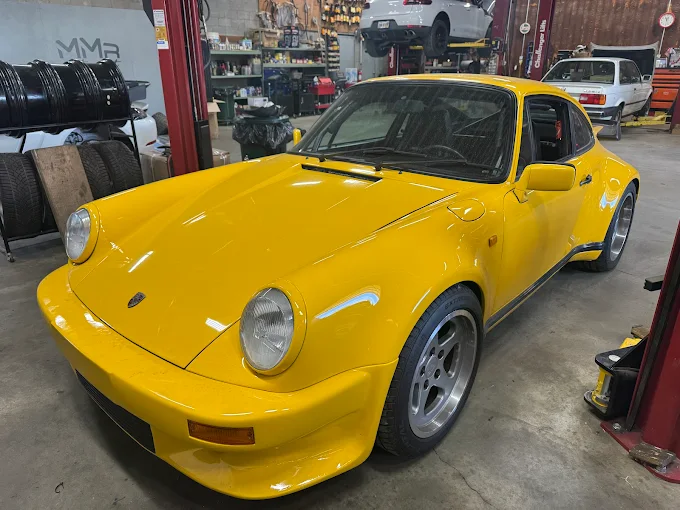 Yellow classic air-cooled Porsche 911 inside the MMr Autosport shop
