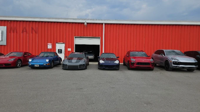 Row of Porsches parked in front of the red MMr Autosport building