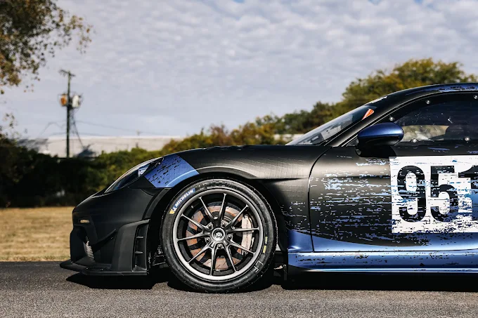 Close side view of a black and blue Porsche race car numbered 953