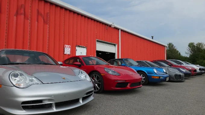 Angled view of a row of Porsches outside the red MMr Autosport building