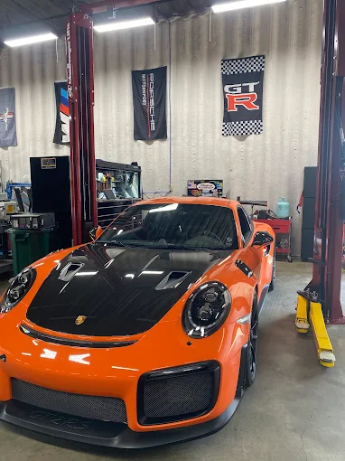 Orange Porsche 911 GT2 RS between the lifts inside MMr Autosport