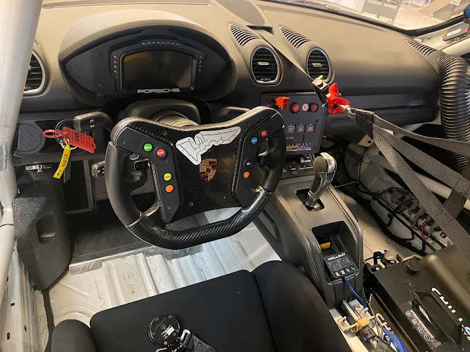 Cockpit of the Porsche race car with carbon steering wheel and roll cage