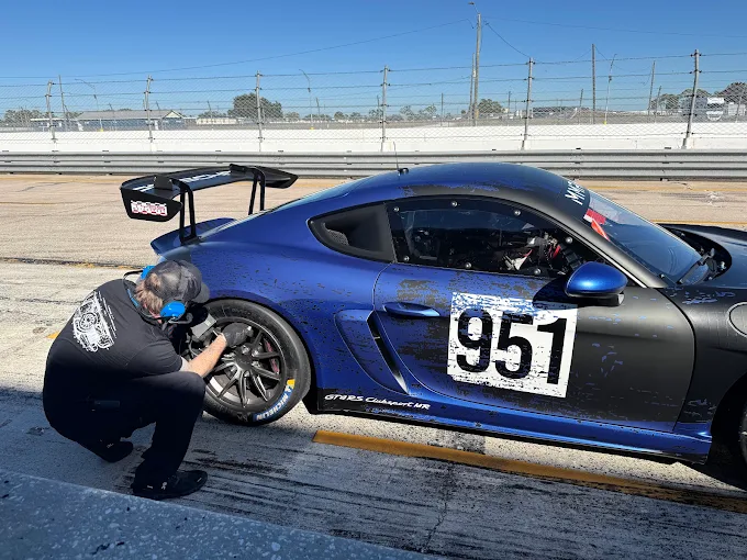 Crew member working on the wheel of the number 951 Porsche in the pit lane