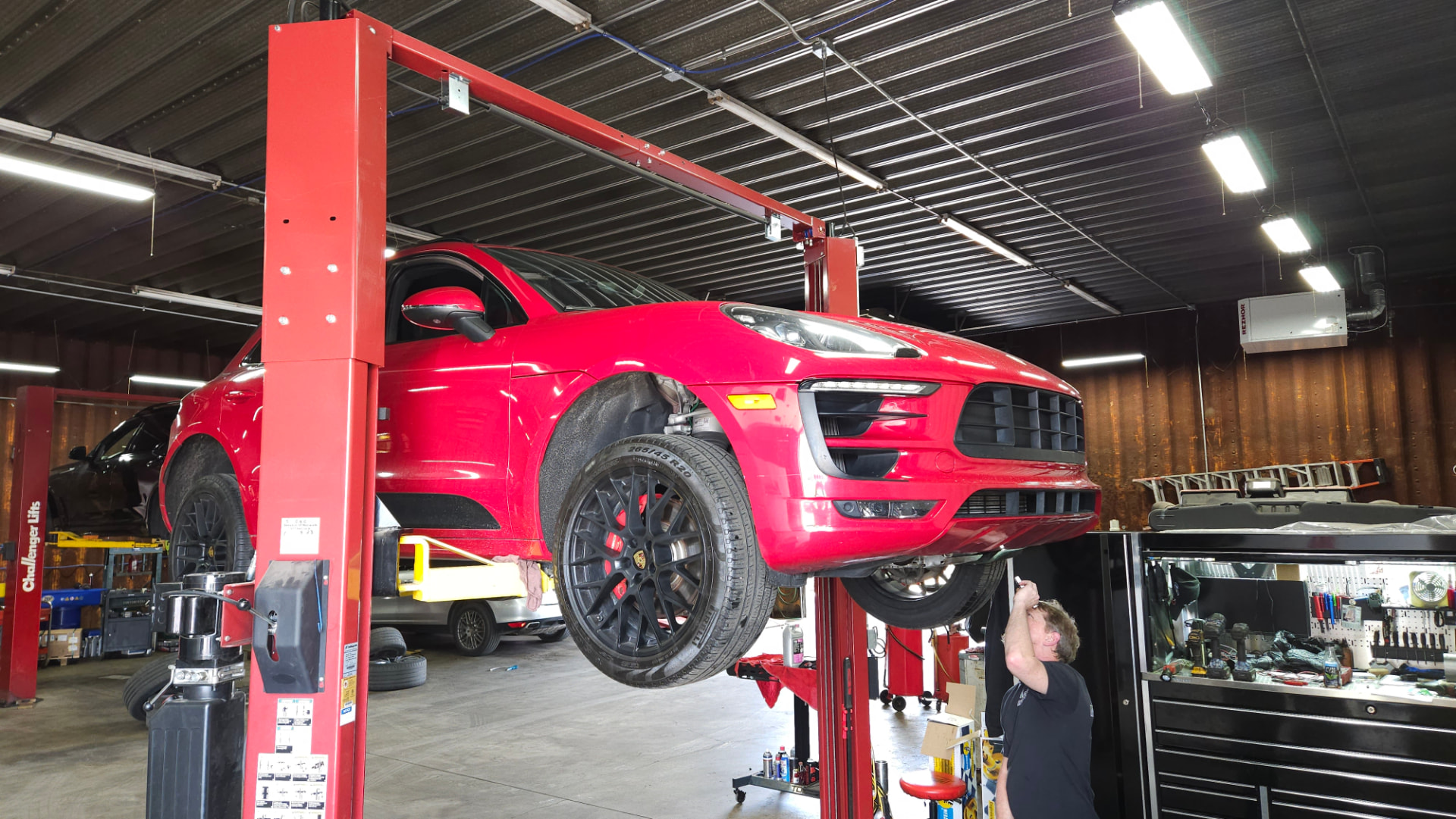 Red Porsche Macan raised on a vehicle lift while being serviced