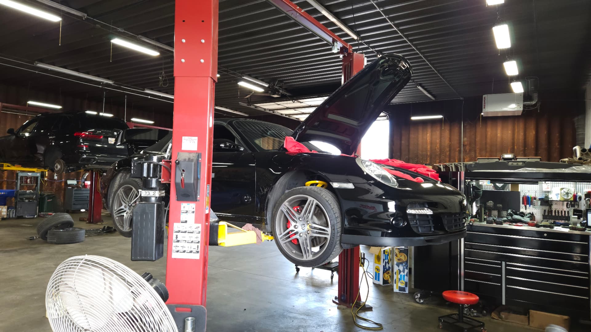 Black Porsche 911 raised on a vehicle lift inside MMr Autosport